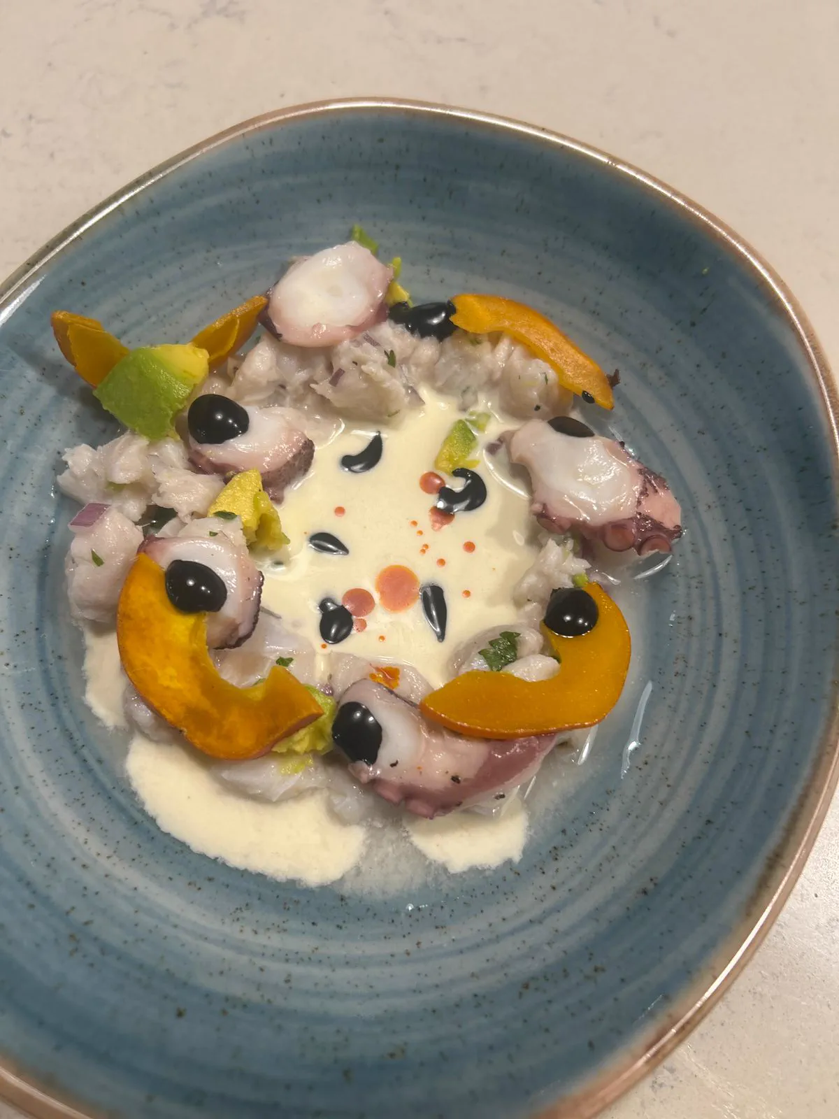 Ceviche con leche de tigre, palmito, pejibaye y aguacate en un cuenco azul